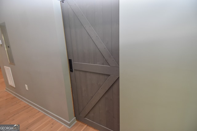interior details featuring a barn door, baseboards, visible vents, and wood finished floors