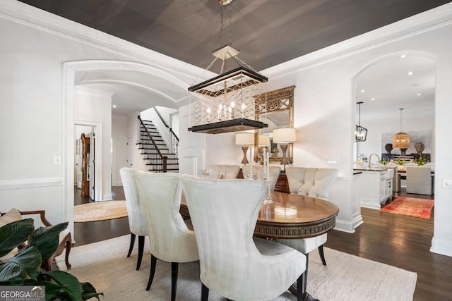 dining area with stairway, dark wood-style flooring, crown molding, and arched walkways