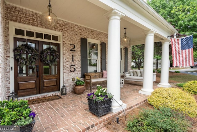 doorway to property featuring a porch, french doors, and brick siding