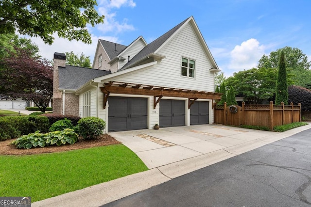 view of side of home featuring fence, an attached garage, driveway, a chimney, and a shingled roof