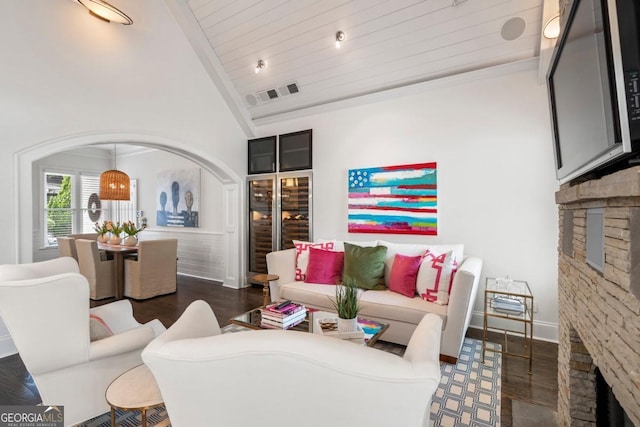 living room featuring vaulted ceiling, dark wood-style flooring, a fireplace, and visible vents
