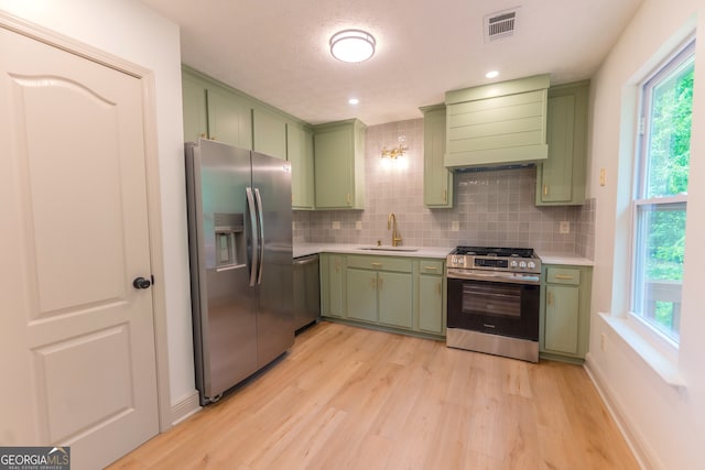 kitchen with a sink, stainless steel appliances, light countertops, and green cabinetry