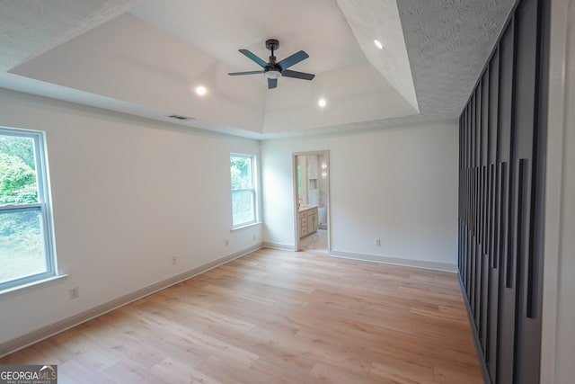 unfurnished bedroom featuring recessed lighting, baseboards, light wood finished floors, visible vents, and a raised ceiling