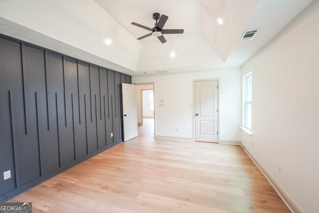 unfurnished bedroom with a tray ceiling, light wood-type flooring, and visible vents