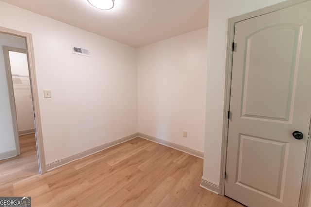 unfurnished room featuring light wood finished floors, visible vents, and baseboards