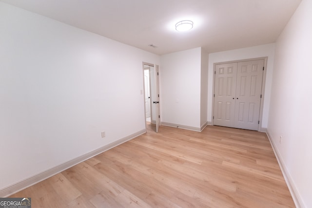 unfurnished bedroom with a closet, light wood-type flooring, and baseboards