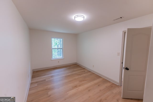 spare room with baseboards, light wood-style floors, and visible vents