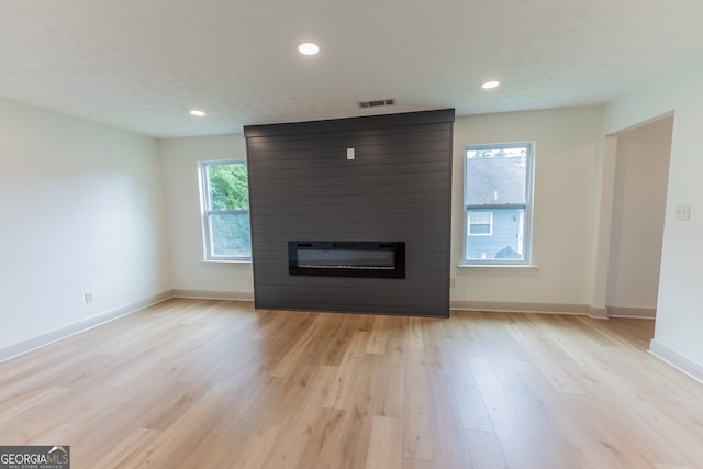 unfurnished living room with light wood-type flooring, visible vents, baseboards, a large fireplace, and recessed lighting