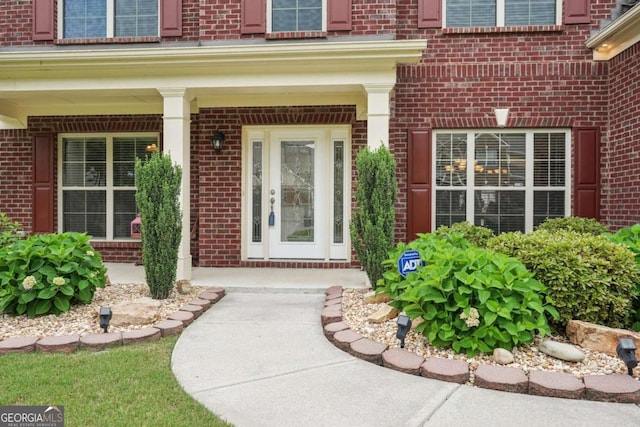 doorway to property with a porch and brick siding