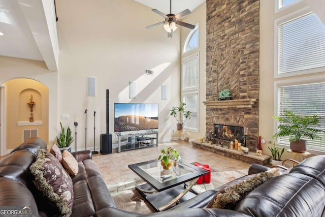 living room with ceiling fan, a towering ceiling, a wealth of natural light, and visible vents