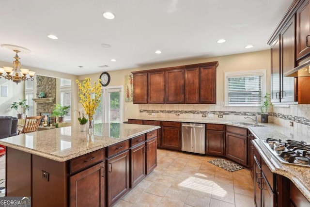 kitchen featuring light stone counters, a healthy amount of sunlight, appliances with stainless steel finishes, and decorative backsplash
