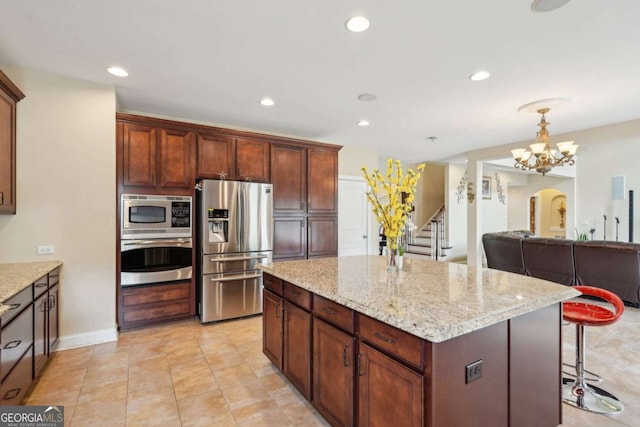 kitchen featuring a kitchen island, stainless steel appliances, light stone counters, and recessed lighting