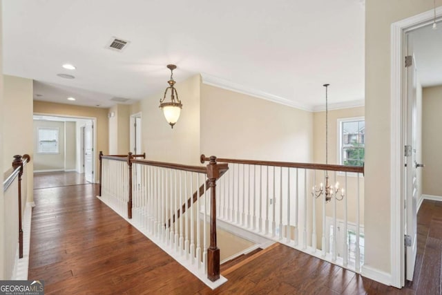 hall with an upstairs landing, hardwood / wood-style flooring, a wealth of natural light, and visible vents