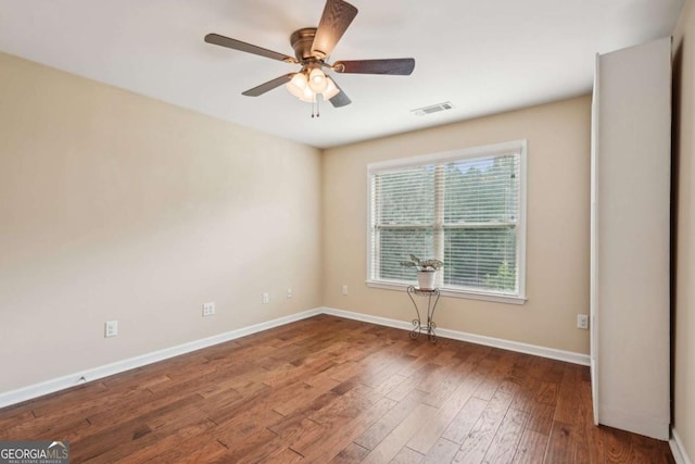 empty room featuring visible vents, baseboards, a ceiling fan, and hardwood / wood-style flooring
