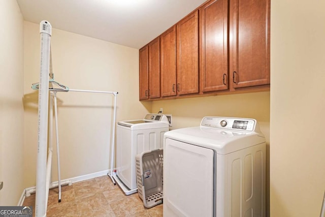 laundry room with separate washer and dryer, cabinet space, and baseboards