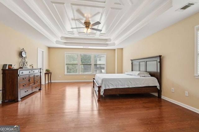 bedroom with a tray ceiling, visible vents, wood finished floors, and ornamental molding