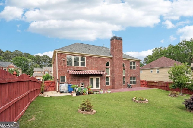back of property featuring a fenced backyard, a chimney, brick siding, and a lawn