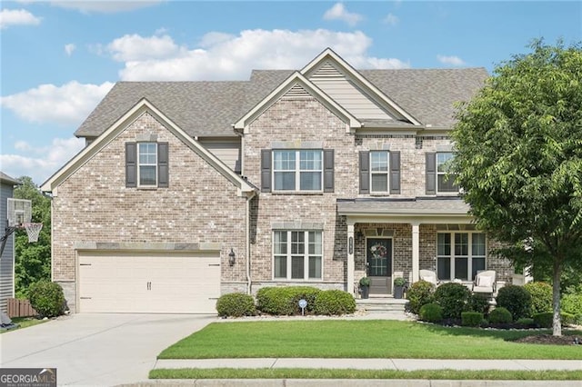craftsman house featuring a front yard, an attached garage, brick siding, and driveway