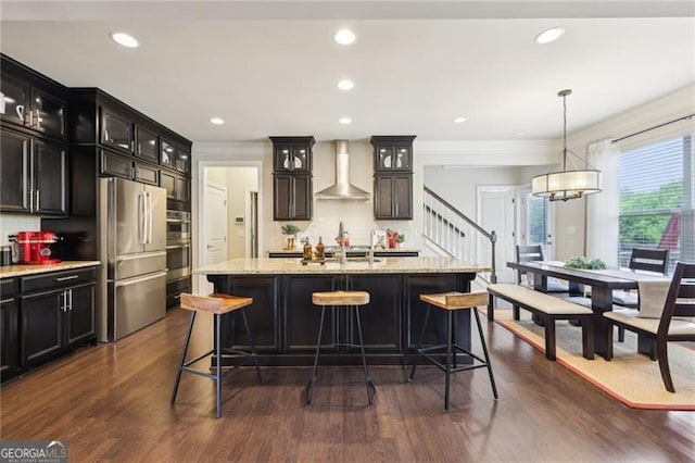 kitchen with glass insert cabinets, a kitchen breakfast bar, decorative backsplash, wall chimney exhaust hood, and stainless steel appliances