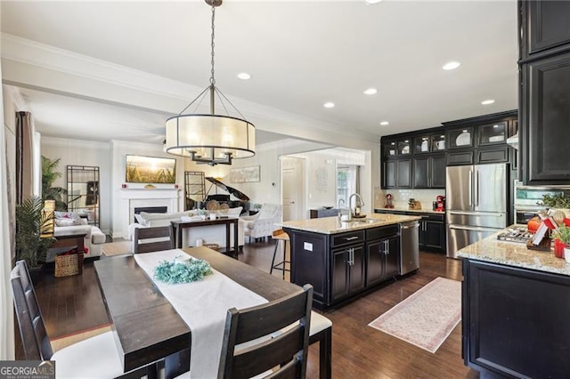 kitchen with a sink, open floor plan, crown molding, a chandelier, and appliances with stainless steel finishes
