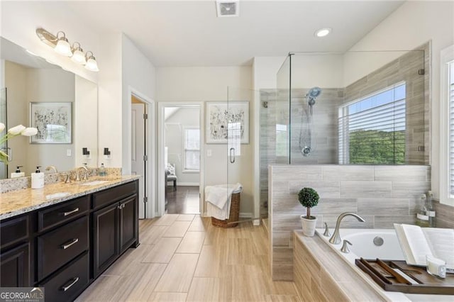 bathroom featuring a stall shower, vanity, plenty of natural light, and visible vents