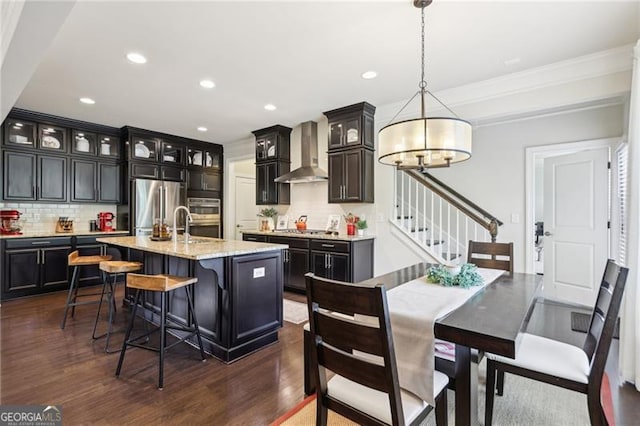 kitchen featuring a chandelier, wall chimney exhaust hood, stainless steel appliances, and tasteful backsplash