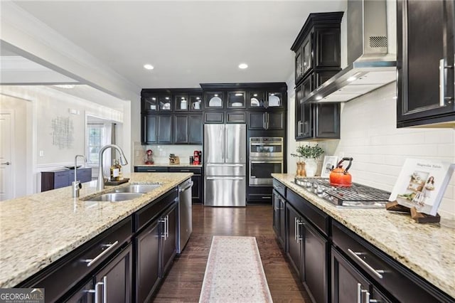 kitchen featuring glass insert cabinets, dark wood-style flooring, a sink, wall chimney range hood, and stainless steel appliances