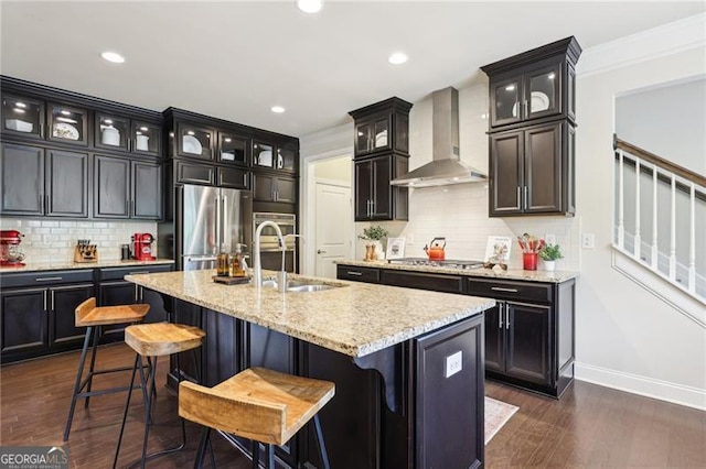 kitchen featuring stainless steel appliances, wall chimney range hood, ornamental molding, decorative backsplash, and baseboards