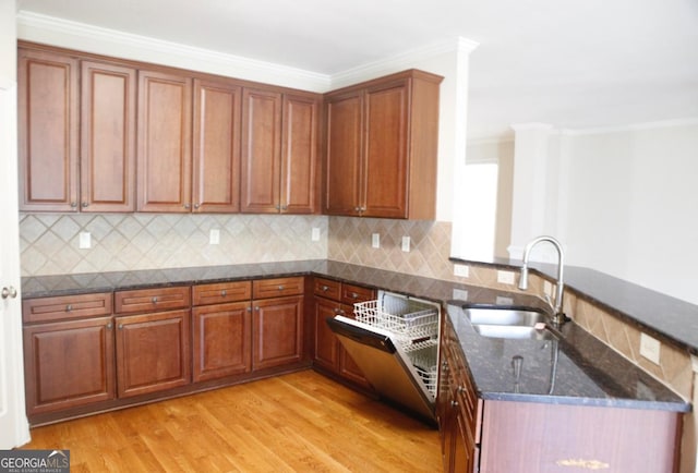 kitchen with a peninsula, light wood finished floors, dark stone countertops, a sink, and crown molding