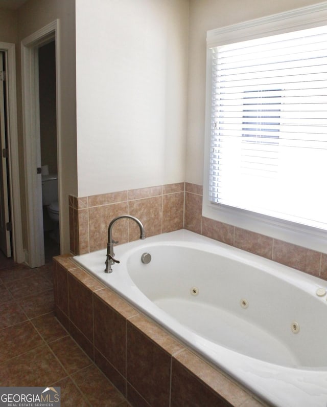 full bath with tile patterned floors, toilet, plenty of natural light, and a whirlpool tub