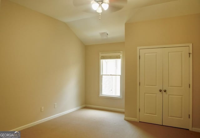 unfurnished bedroom with a closet, carpet, baseboards, ceiling fan, and vaulted ceiling