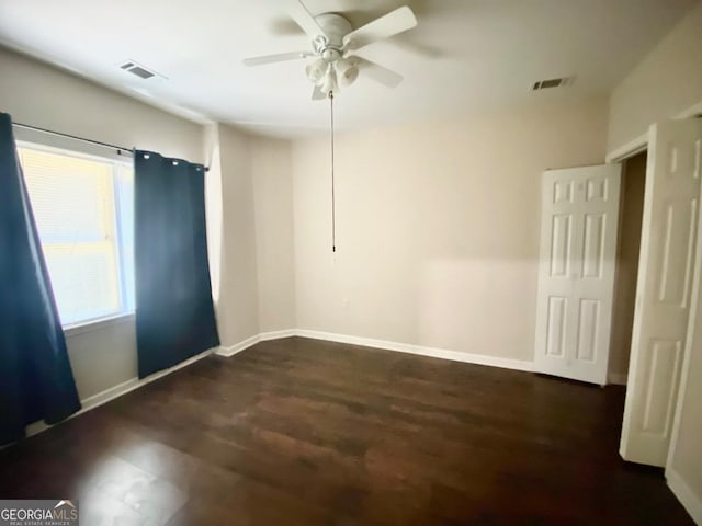 unfurnished room with baseboards, visible vents, wood finished floors, and a ceiling fan
