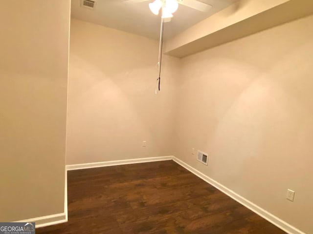 unfurnished room with baseboards, ceiling fan, visible vents, and dark wood-type flooring