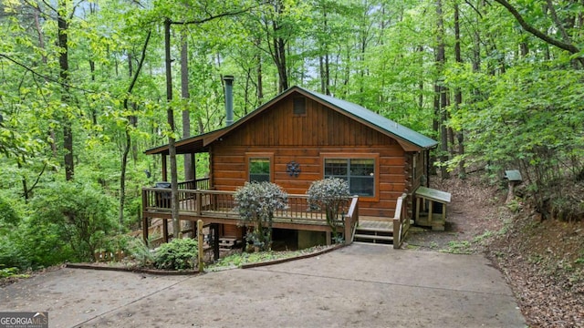 view of front facade featuring a wooden deck and a forest view