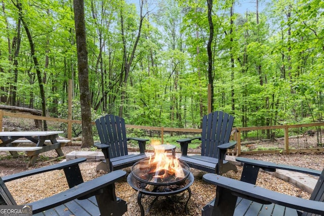 view of patio / terrace with an outdoor fire pit and a view of trees