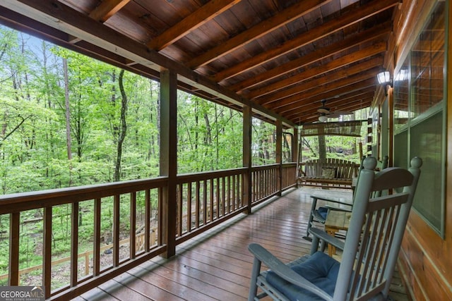 wooden deck with ceiling fan and a view of trees