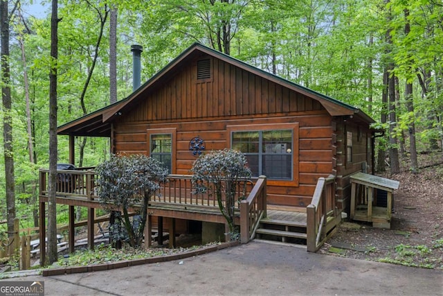 view of front of house with a wooden deck and a forest view