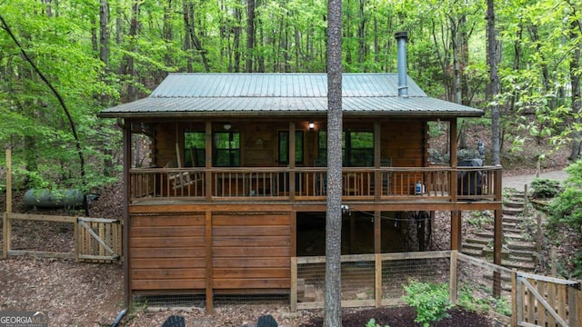 chalet / cabin featuring metal roof, a wooded view, and a porch