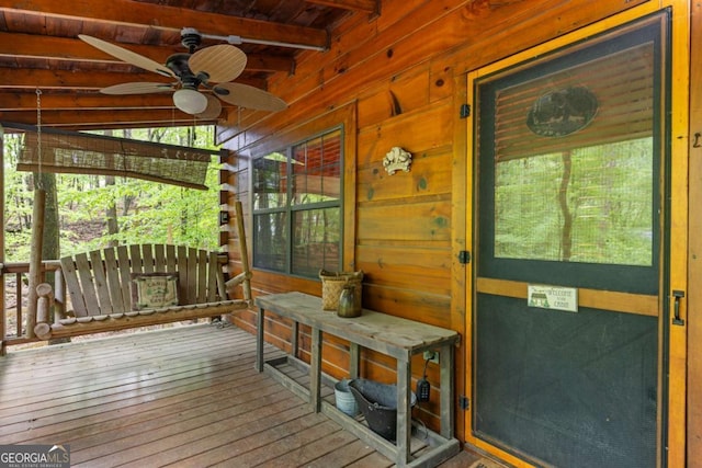 sunroom featuring beam ceiling, a ceiling fan, and a healthy amount of sunlight