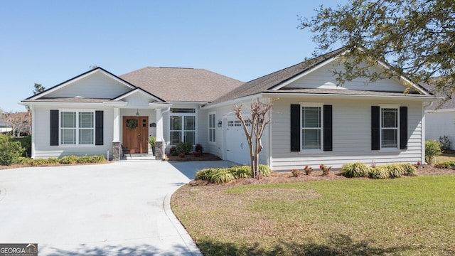 view of front facade featuring roof with shingles, concrete driveway, a garage, and a front lawn