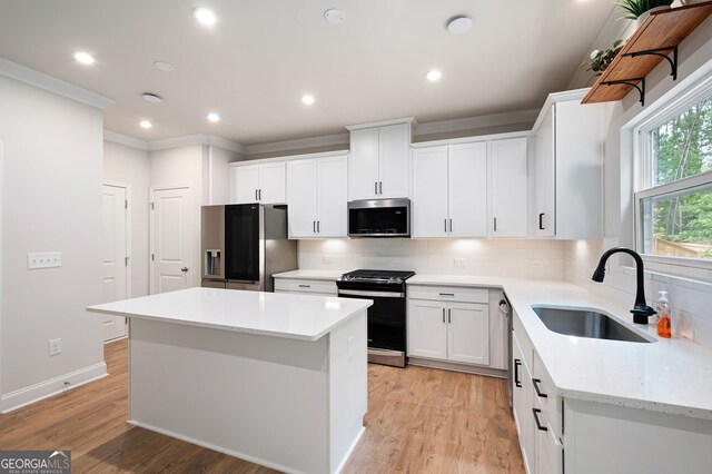 63 Brookstone Park E, Acworth, GA 30101 - kitchen with stainless steel appliances, a sink, decorative backsplash, a kitchen island, and crown molding