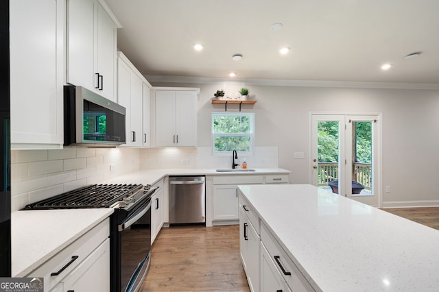 63 Brookstone Park E, Acworth, GA 30101 - kitchen with stainless steel appliances, a sink, light wood-type flooring, white cabinetry, and ornamental molding