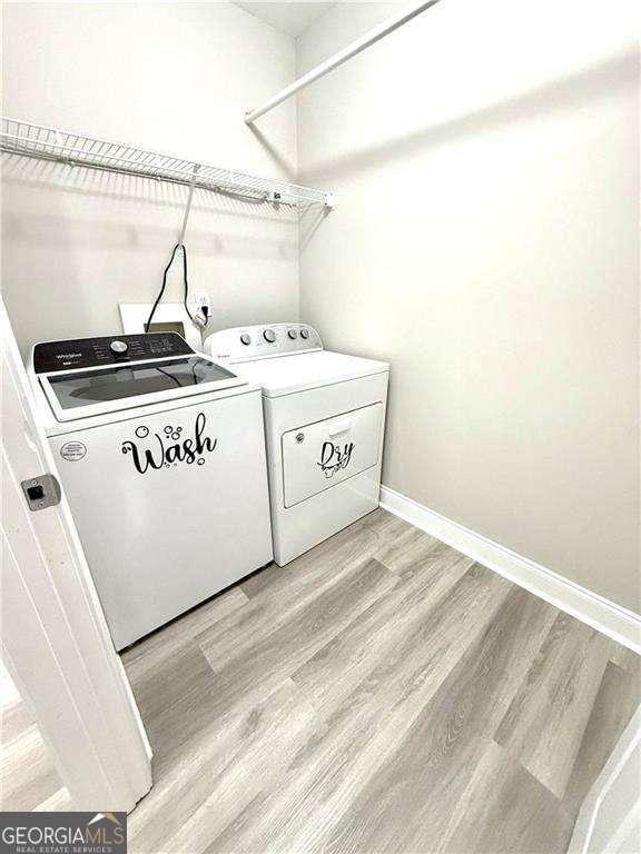 6945 Autumn Hills Dr, Cumming, GA 30028 - laundry area with baseboards, laundry area, light wood-type flooring, and washer and clothes dryer