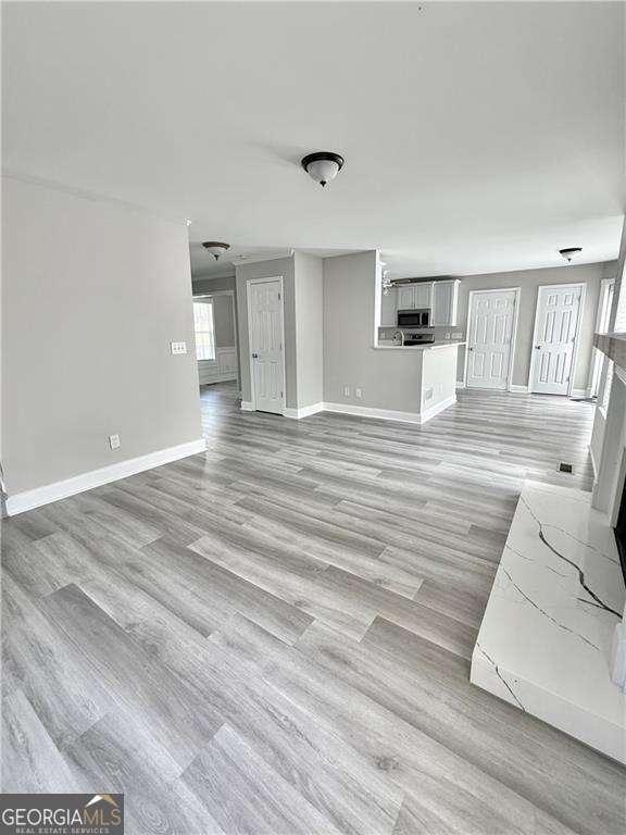 6945 Autumn Hills Dr, Cumming, GA 30028 - unfurnished living room featuring baseboards and light wood-style flooring