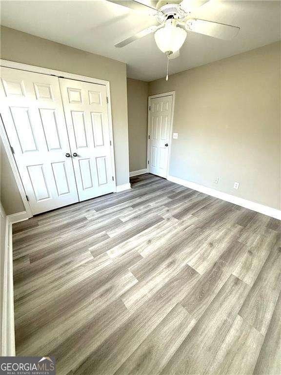 6945 Autumn Hills Dr, Cumming, GA 30028 - unfurnished bedroom with baseboards, a closet, ceiling fan, and wood finished floors