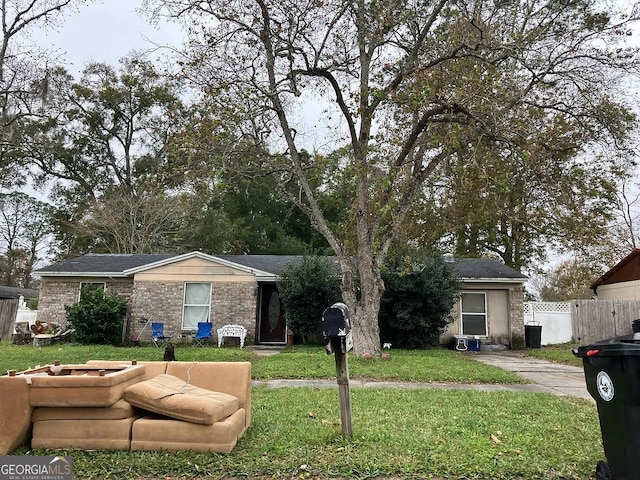 single story home with fence, brick siding, and a front yard