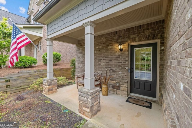 property entrance with a porch and brick siding