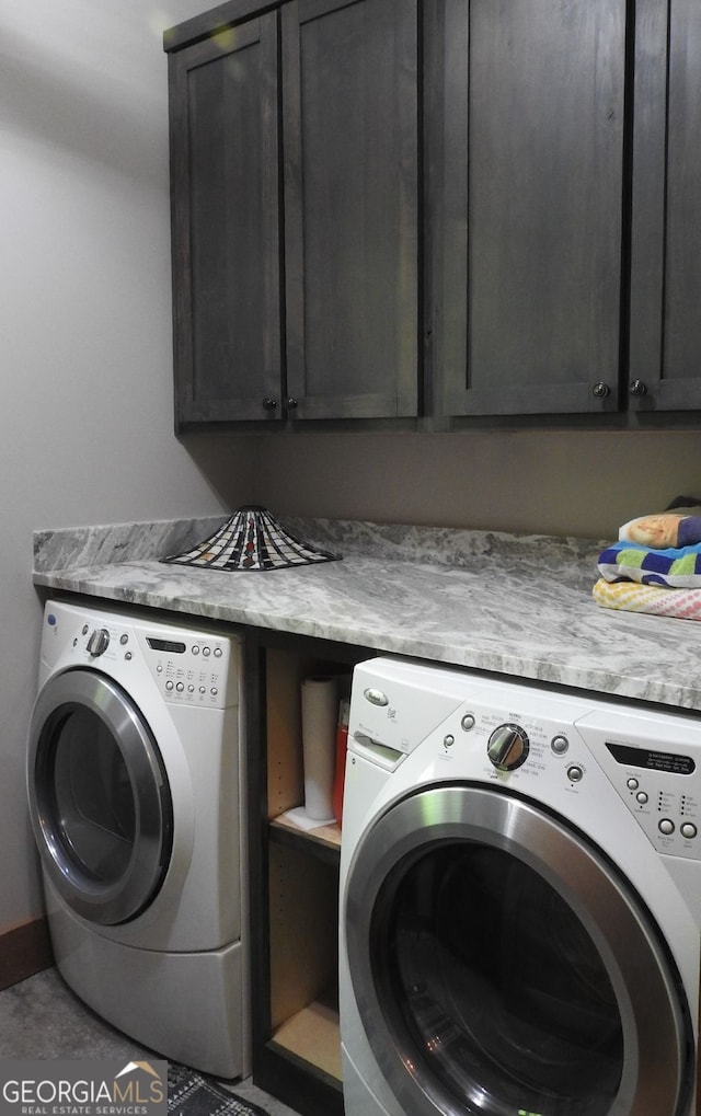 washroom featuring washing machine and dryer, cabinet space, and baseboards