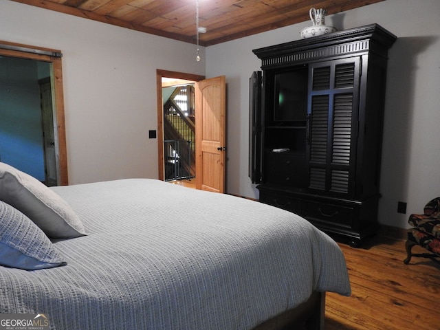 bedroom with wood ceiling, baseboards, and wood finished floors