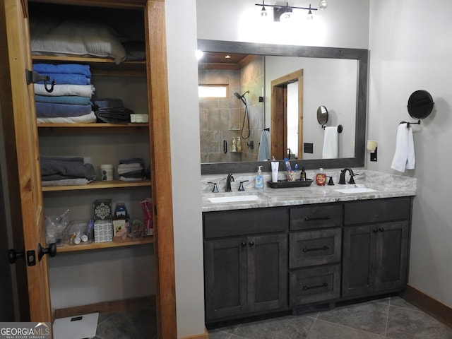 bathroom featuring a tile shower, tile patterned floors, double vanity, and a sink